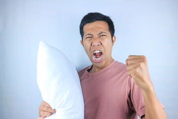 Excited facial expression of young Asian man hug a pillow, preparing to sleep. Bedtime concept