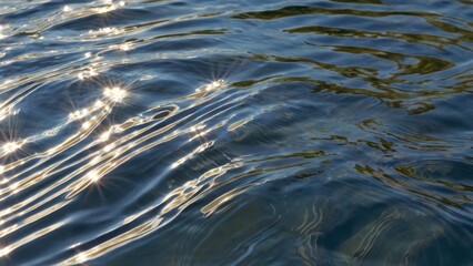 Close-up of sunlight reflecting on rippling water, creating sparkling highlights and fluid, dynamic patterns in a tranquil scene.