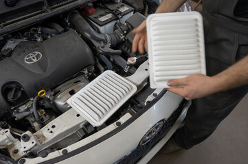 Mechanic holding old and new cabin air car filters. 