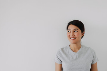 Happy Thai asian woman smiling look at empty, isolated over white background wall.