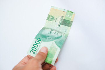 hand holding twenty thousand rupiah isolated on white background