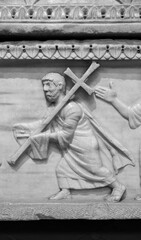 Black and white photo showing in detail a carved sculpture on a marble wall of Jesus carrying a cross