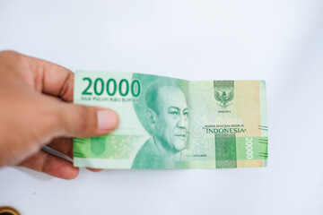 hand holding twenty thousand rupiah isolated on white background