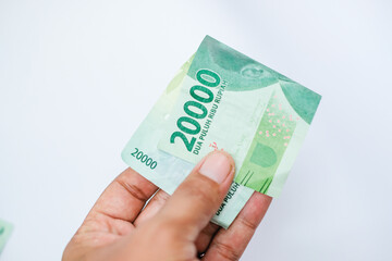 hand holding twenty thousand rupiah isolated on white background