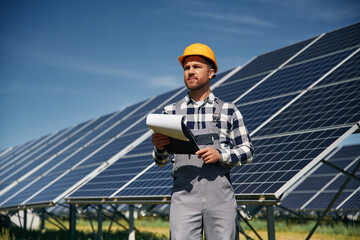 Cheerful engineer with photovoltaic solar panels outdoors at daytime