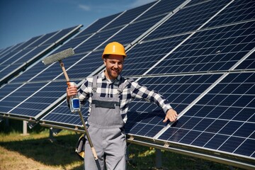 Procedure of cleaning the surface. Engineer with photovoltaic solar panels outdoors at daytime