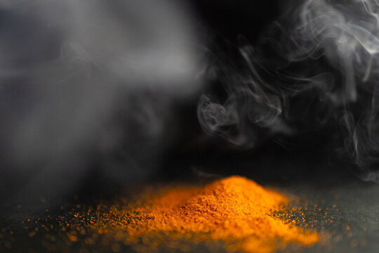 Horizontal picture of pile of red parika with smoke around it.Black background
