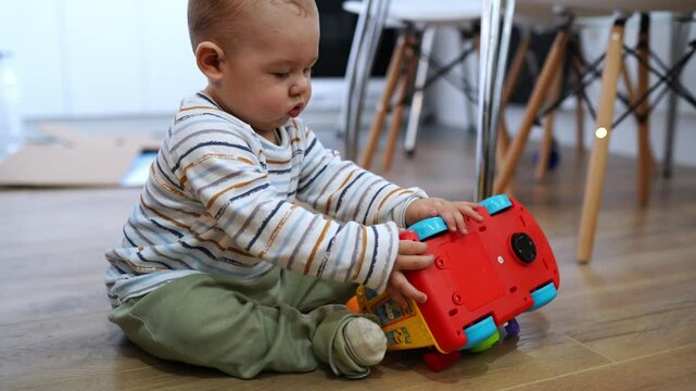 The baby is playing with the car. Baby boy 8 months old playing with a toy