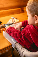 Baby while having fun in the mountain house with various games while sitting in the high chair baby food