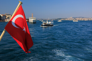 Turkish flag, on a red background white star and moon. Turkish flag flies in the wind against the backdrop of Istanbul