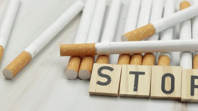 tas de cigarettes, vue du dessus, avec le mot Stop &eacute;crit en lettres en bois dessus.