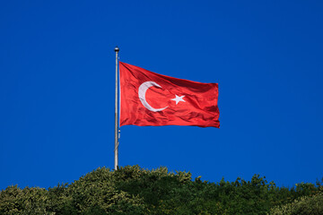 Turkish flag, on a red background white star and moon. Turkish flag flies in the wind against the backdrop of Istanbul