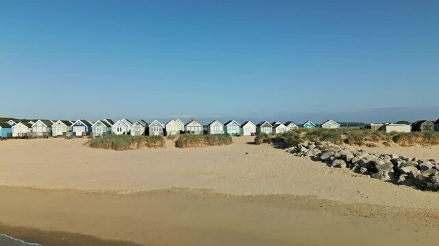 4k video of drone flying toward and over beach huts from sea in Mudeford, Dorset