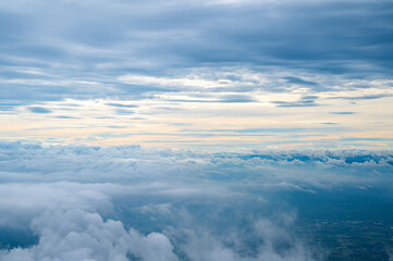 Aerial view of mountain range surrounded by low clouds at sunset and the asian sky in background as seen from the plane and Mountain above.