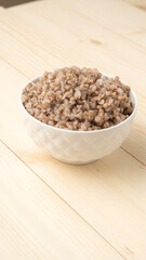 buckwheat porridge in a round white plate on a wooden table.