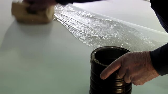 Soccer Ball Manufacturing Process: Worker Applying Adhesive to Synthetic Leather Sheet at Factory. Close-Up Shot. 4K Resolution.