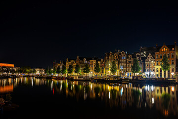 Night photo of traditional dutch houses in front of a canal Amsterdam