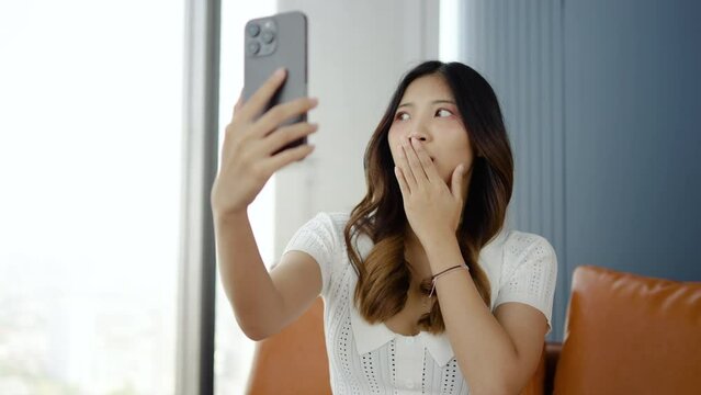 Shell-shocked young woman covers mouth with hands in dismay over mistake. secret worried expression when video call talking to a friend or lover on the phone, Try to cover it up so that nothing happen