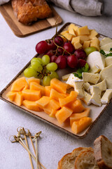 Cheese plate with different cheese, grapes and melon.