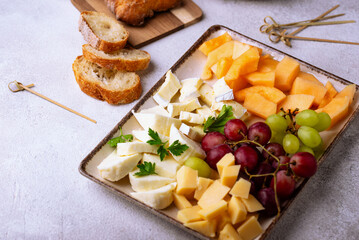 Cheese plate with different cheese, grapes and melon.