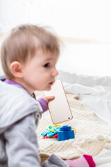 Baby girl playing with smartphone on a bed