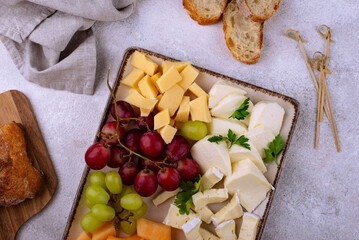 Cheese plate with different cheese, grapes and melon.