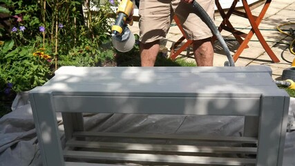 Spray painting garden furniture with water based paint in white with an electric sprayer