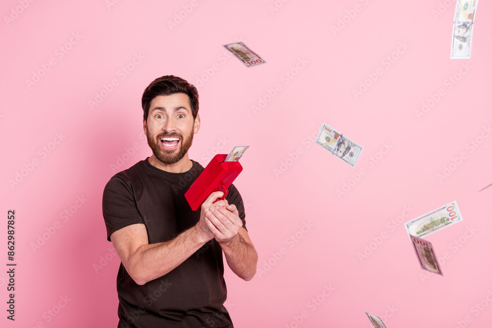 Sticker Portrait of impressed man with stylish bristle wear brown shirt throwing money banknotes from gun isolated on pink color background