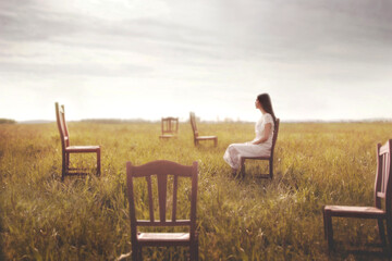 surreal woman sitting on a chair in the middle of the field surrounded by other empty chairs,...