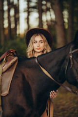 Naklejka premium A young beautiful woman walks with her horse in the forest in early autumn. Walking with a horse in the forest.