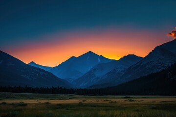 A captivating mountain range during sunset, with the sky transitioning from orange to deep blue, and the mountains 