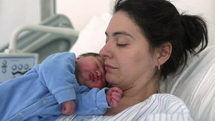 Mother and newborn baby at hospital after childbirth. Authentic real life new mom holding her infant during first day of life together