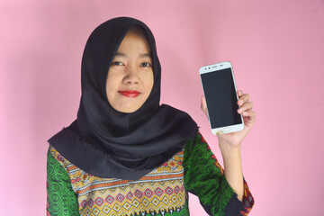 Dissatisfied young Asian girl standing holding mobile phone. Isolated on background