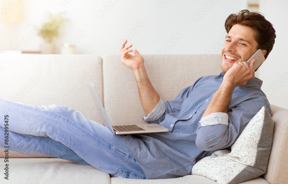 Poster a man sits on a couch with his legs outstretched, smiling and talking on the phone while holding a l