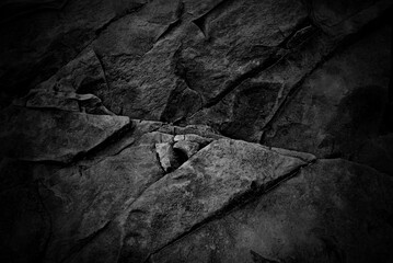 Black rock texture, darkened background of a black rock wall