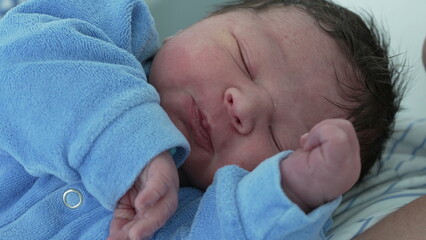 Newborn baby close-up face during the first day of life. infant child with eyes closed initial...