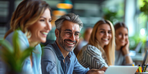 Obraz premium Smiling business people having a discussion in an office crowded around a laptop 