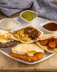 Colombian Arepas filled with pulled beef, pulled chicken, fried pork skin, cheese, quail eggs, jam and chorizo