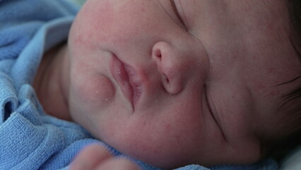 Newborn baby macro close-up face during first day of life after childbirth sleeping. Adorable infant