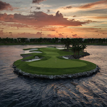 an image of a picturesque par 3 golf course featuring an island green against sunset background.