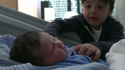 Sibling Interaction in Hospital/ Newborn Baby Brother Rests in Bed as Family Celebrates Early Days