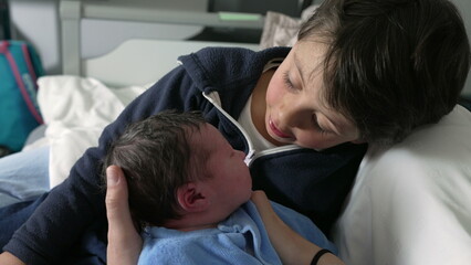 Young boy meeting his newborn baby at hospital in tender heartwarming moment between brothers at hospital, first day of life of an infant being welcomed by sibling, eskimo kiss