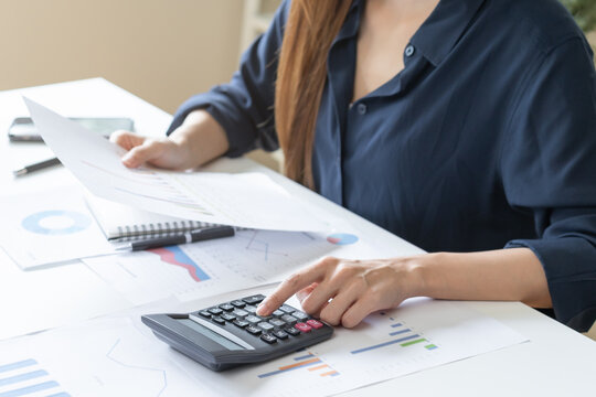 Account finance, analysis asian business woman hand use pen for calculate budget, cost and income of company from on charts, reports paperwork, plan spend money expenses, working on desk at home.