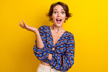 Portrait of young surprised girl wearing trendy blouse hold in arm invincible product promoting ads...
