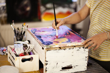 Girl using brush and tool on an artistic painting. Female artist creating art.