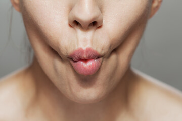 Close-up of a woman making a kiss face, pink lips and natural skin texture