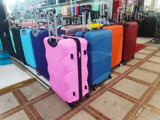 many new multi-colored large plastic suitcases on wheels. Concept of travel, vacation, tourism.