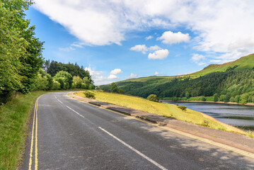 Deserted winding road running along a reservoir in the mountains on a clear summer day
