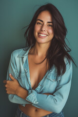 Fototapeta premium Sensual brunette girl in denim crop top with arms crossed on blue background. Generative AI.