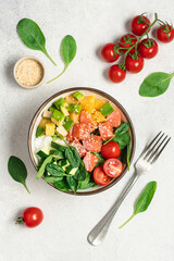 Salmon bowl with spinach, rice, avocado, tomato, cucumbers on a white background, top view. Poke bowl, healthy eating